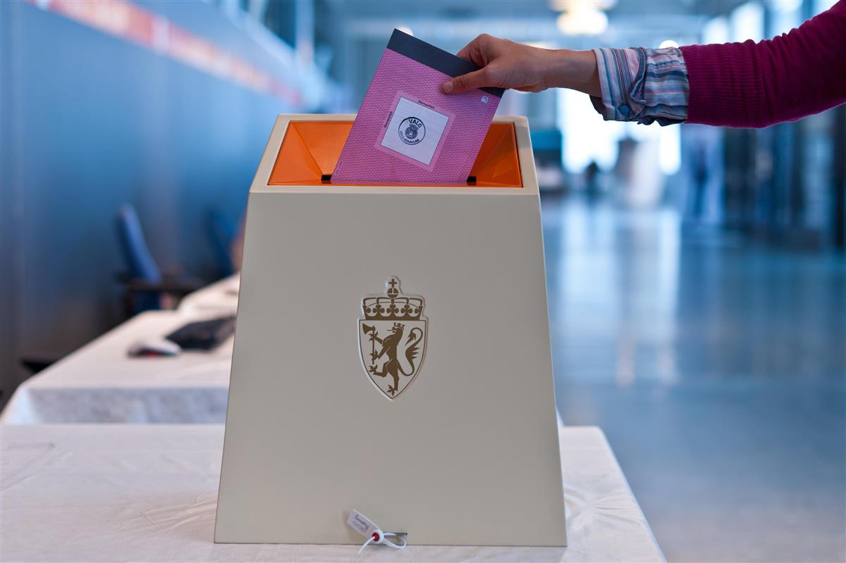 Person legger stemmeseddel i valgurne - Klikk for stort bilde